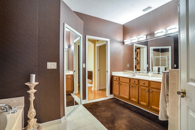 bathroom with tile patterned flooring, a washtub, vanity, and a textured ceiling