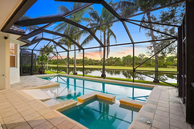 pool at dusk featuring a patio, a lanai, an in ground hot tub, and a water view