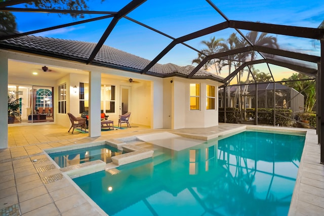 pool at dusk with ceiling fan, a lanai, and a patio