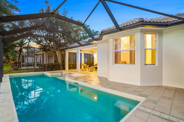 pool at dusk featuring a patio area and a lanai