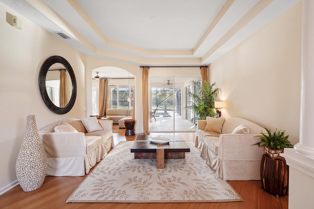 living room featuring hardwood / wood-style floors and a tray ceiling