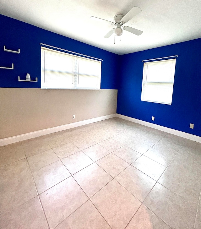 spare room featuring a wealth of natural light, ceiling fan, and light tile patterned flooring