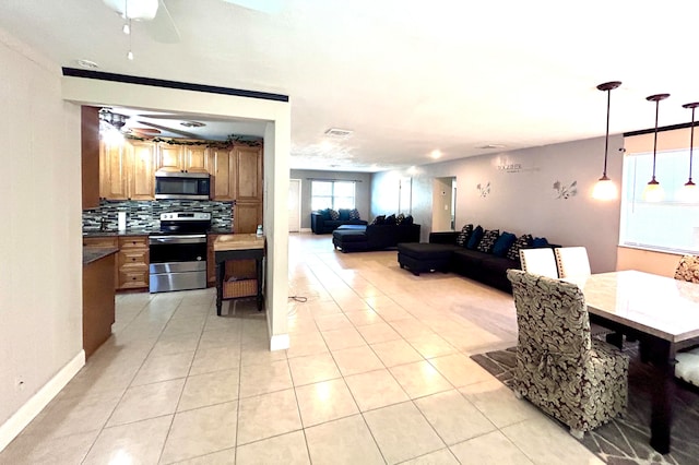 interior space with stainless steel appliances, hanging light fixtures, tasteful backsplash, light tile patterned flooring, and ceiling fan