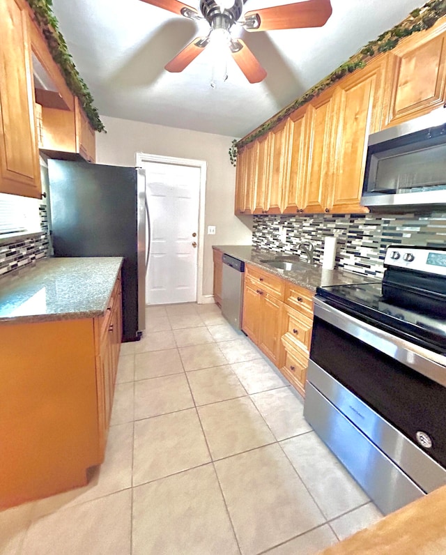 kitchen featuring stainless steel appliances, decorative backsplash, sink, light tile patterned floors, and ceiling fan