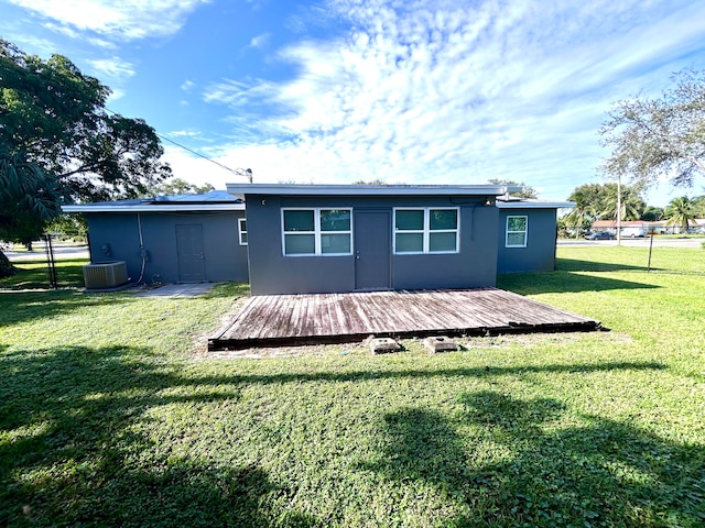 rear view of property featuring a lawn, a wooden deck, and cooling unit