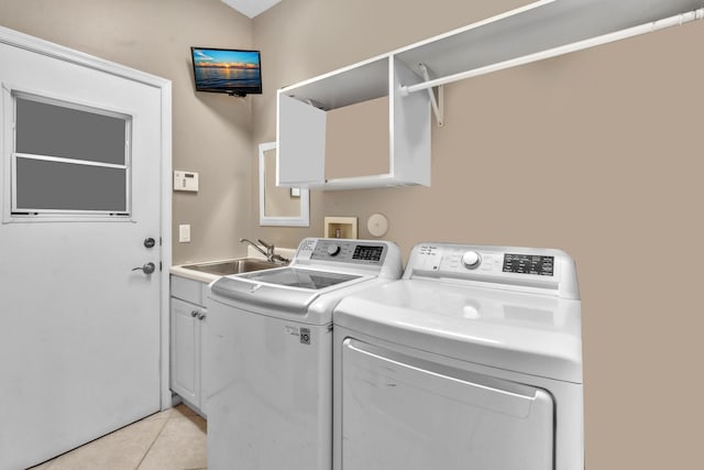 clothes washing area with light tile patterned flooring, cabinets, sink, and washer and dryer