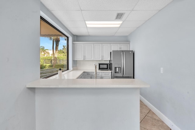 kitchen with stainless steel fridge, a paneled ceiling, white cabinetry, built in microwave, and kitchen peninsula