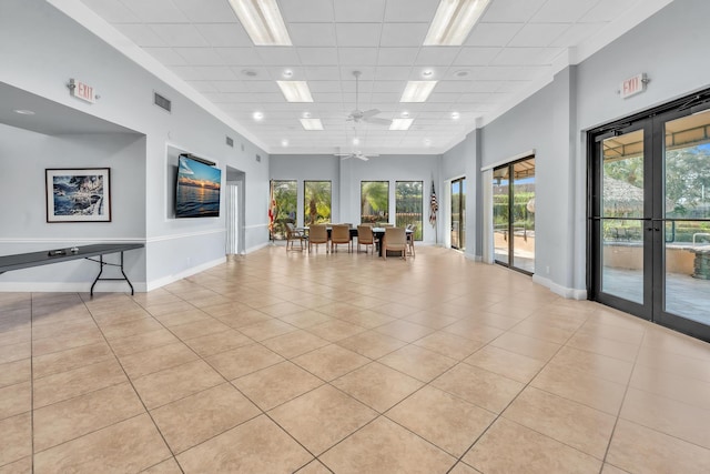 tiled spare room with french doors, a paneled ceiling, ceiling fan, and a high ceiling