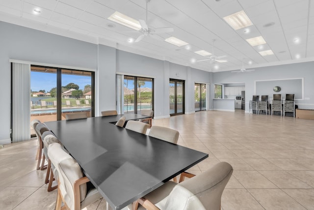 tiled dining room with a towering ceiling, a drop ceiling, and ceiling fan