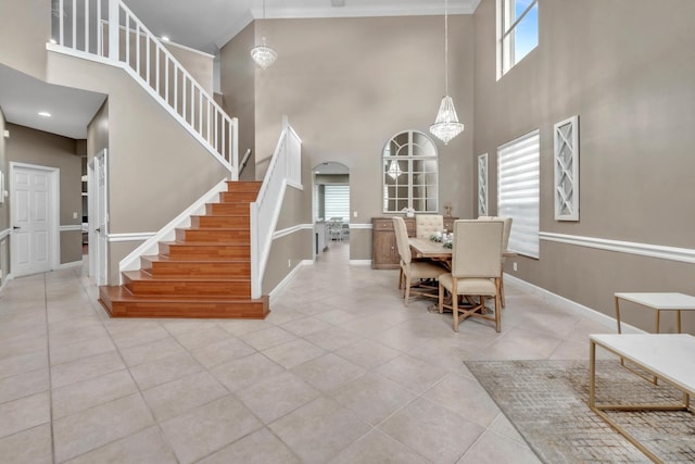 dining room featuring crown molding, a towering ceiling, an inviting chandelier, and light tile patterned floors