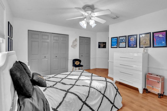 bedroom with multiple closets, ceiling fan, and light wood-type flooring