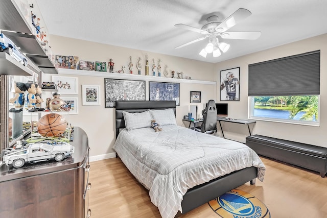 bedroom featuring ceiling fan, a textured ceiling, and light wood-type flooring