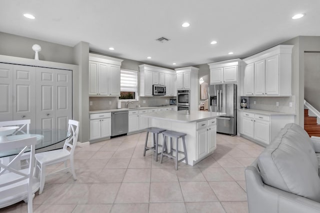 kitchen with a kitchen island, white cabinetry, sink, a kitchen breakfast bar, and stainless steel appliances