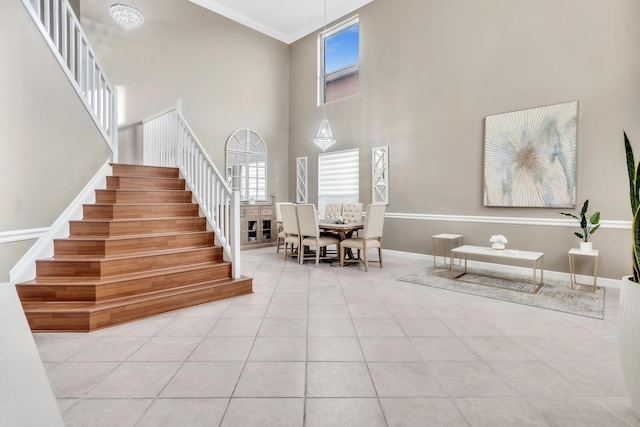 stairs featuring tile patterned flooring, ornamental molding, and a towering ceiling