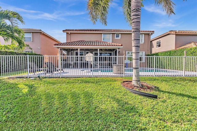 back of house with a fenced in pool, a lawn, and a sunroom