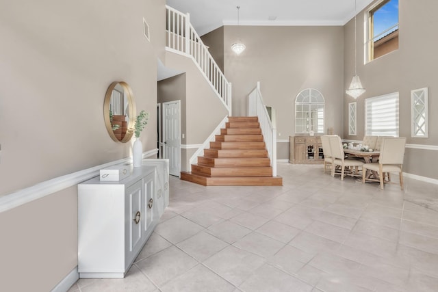 stairs featuring crown molding, tile patterned floors, and a towering ceiling