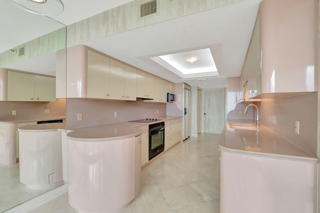 kitchen featuring black appliances, sink, light tile patterned flooring, and a raised ceiling