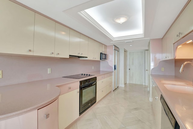 kitchen featuring black appliances, sink, cream cabinets, and a raised ceiling