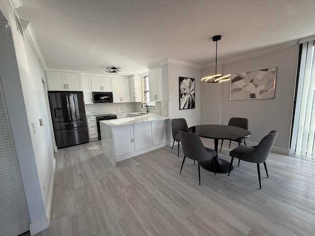 kitchen with white cabinetry, hanging light fixtures, light hardwood / wood-style flooring, kitchen peninsula, and black appliances