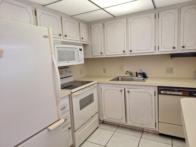 kitchen featuring white appliances, a paneled ceiling, sink, and light tile patterned flooring