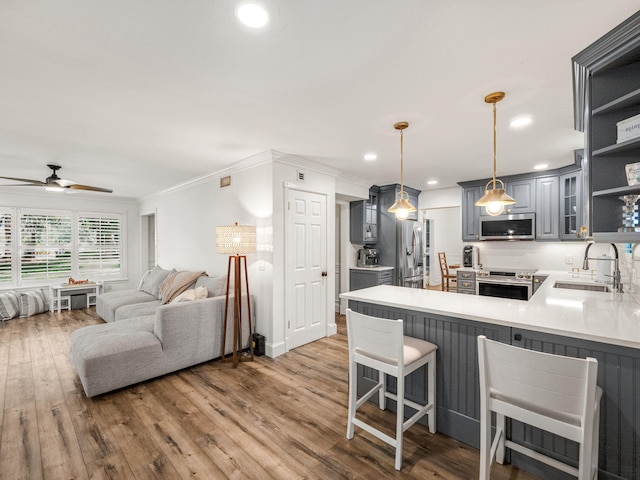 kitchen featuring kitchen peninsula, gray cabinetry, stainless steel appliances, sink, and decorative light fixtures