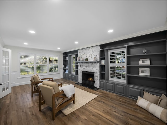 living room with a fireplace, built in shelves, crown molding, and dark hardwood / wood-style floors