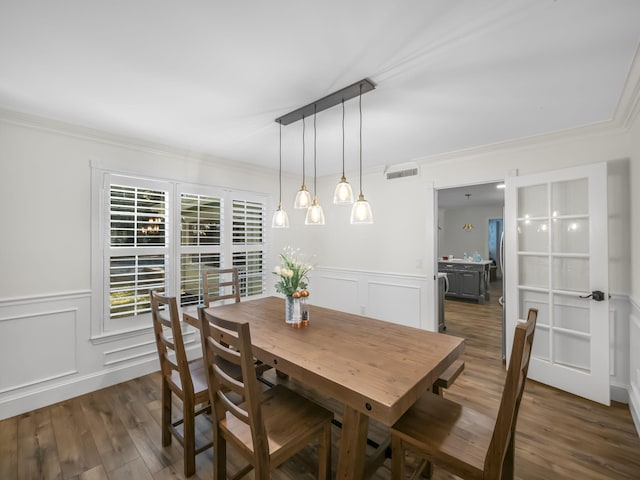 dining area with crown molding and dark wood-type flooring