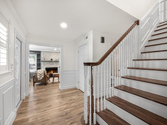 staircase with a fireplace, hardwood / wood-style floors, and crown molding