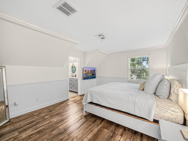 bedroom with a textured ceiling, hardwood / wood-style floors, vaulted ceiling, and ornamental molding