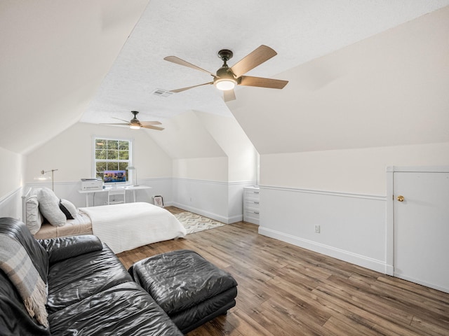 bedroom featuring hardwood / wood-style floors, ceiling fan, lofted ceiling, and a textured ceiling