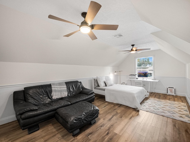 bedroom featuring a textured ceiling, ceiling fan, wood-type flooring, and lofted ceiling