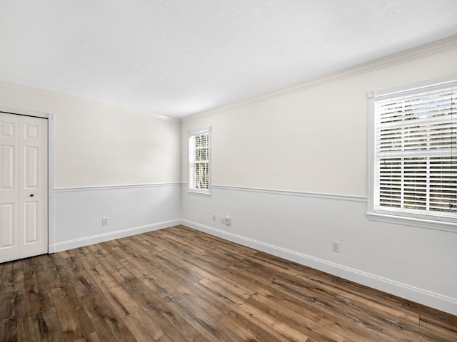 unfurnished room featuring a textured ceiling, crown molding, dark hardwood / wood-style flooring, and plenty of natural light