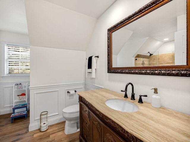 bathroom with hardwood / wood-style floors, vaulted ceiling, vanity, toilet, and walk in shower