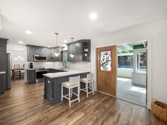 kitchen featuring kitchen peninsula, dark hardwood / wood-style flooring, stainless steel appliances, gray cabinets, and hanging light fixtures