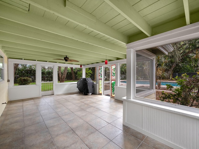 unfurnished sunroom with ceiling fan, a wealth of natural light, wood ceiling, and beam ceiling