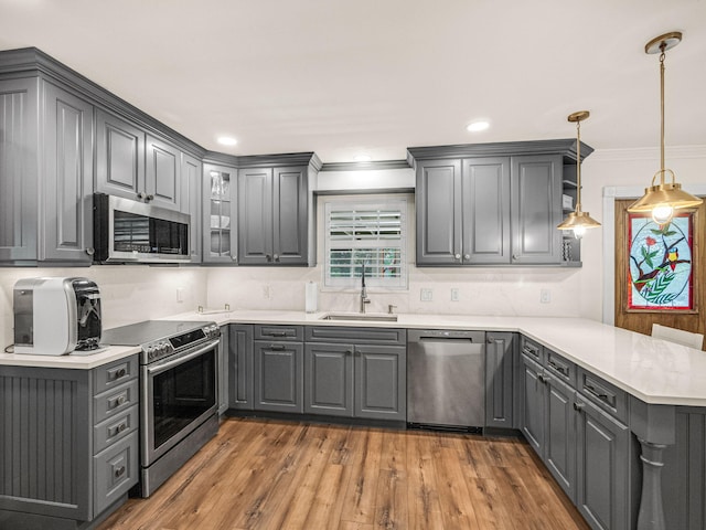 kitchen featuring sink, hardwood / wood-style flooring, appliances with stainless steel finishes, kitchen peninsula, and gray cabinets