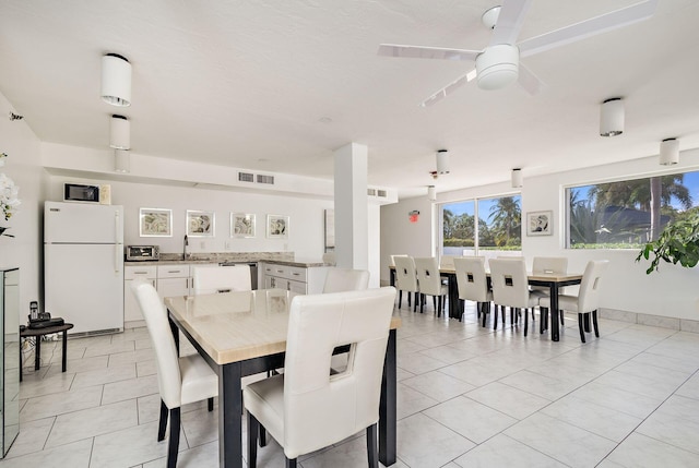 tiled dining space featuring ceiling fan and sink