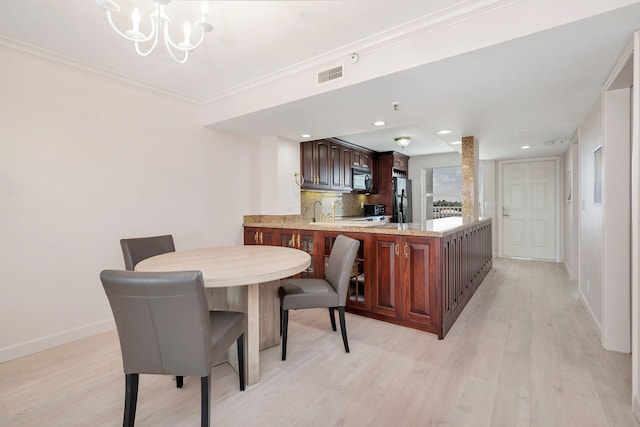 dining space featuring an inviting chandelier, sink, light wood-type flooring, and ornamental molding