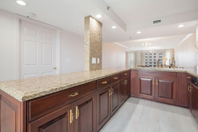 kitchen with light stone countertops, an inviting chandelier, sink, light hardwood / wood-style floors, and kitchen peninsula