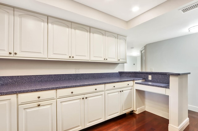 kitchen with kitchen peninsula, white cabinets, and dark hardwood / wood-style floors