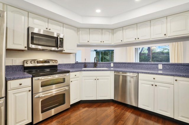 kitchen with dark hardwood / wood-style flooring, stainless steel appliances, white cabinetry, and sink