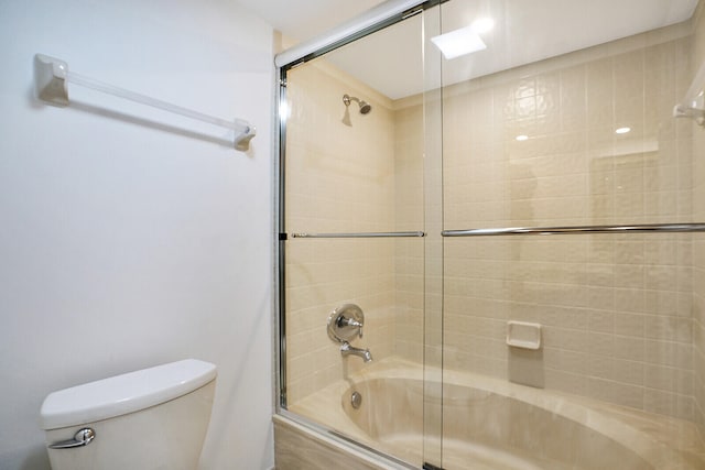 bathroom featuring enclosed tub / shower combo and toilet