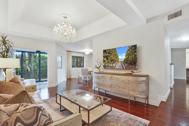 living room with a tray ceiling, dark hardwood / wood-style flooring, and an inviting chandelier