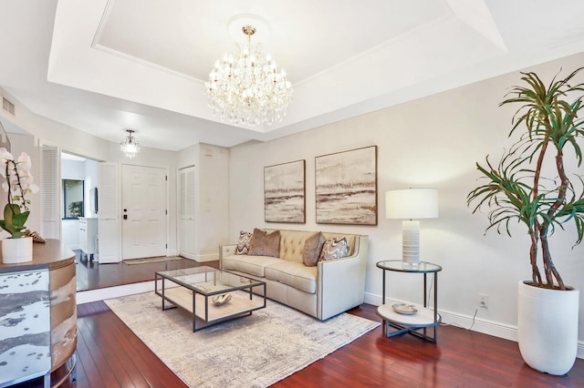 living room with a chandelier, a raised ceiling, and dark wood-type flooring