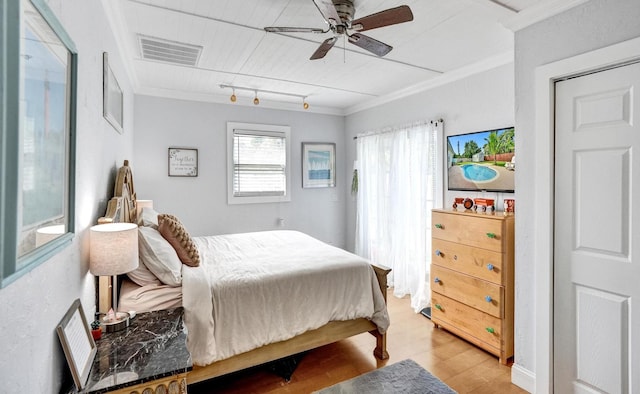 bedroom with light wood-type flooring, rail lighting, ceiling fan, and crown molding