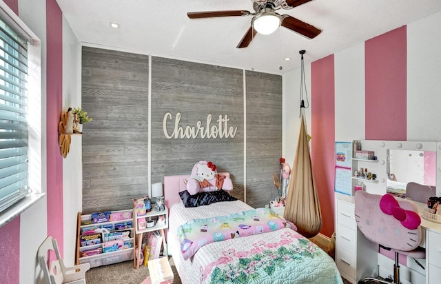 bedroom with a textured ceiling, a closet, ceiling fan, and wood walls