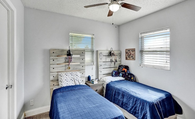carpeted bedroom with a textured ceiling, baseboards, and ceiling fan
