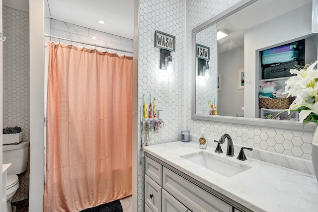 bathroom featuring toilet, decorative backsplash, vanity, and curtained shower