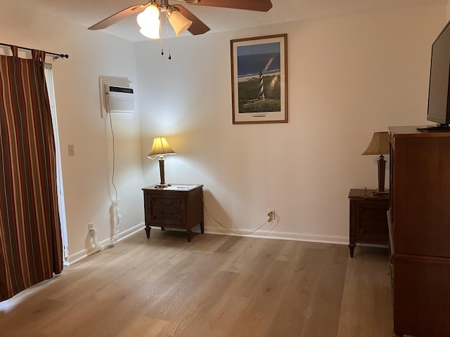 interior space with ceiling fan, light wood-type flooring, a textured ceiling, and a wall unit AC