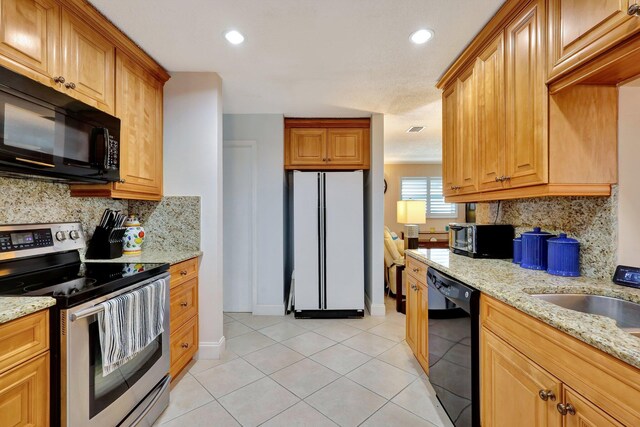 kitchen with black appliances, light tile patterned flooring, light stone countertops, and tasteful backsplash